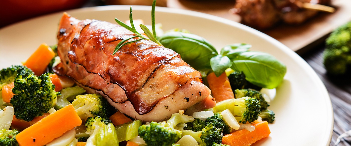 Pollo envuelto en tocino acompañado de verduras al vapor
